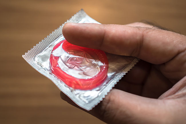 Mann hält Kondompackung in der Hand